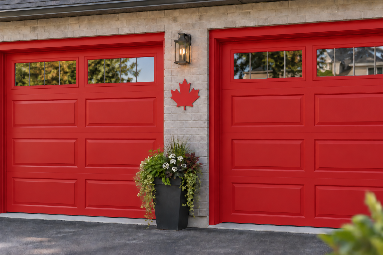 Sixteen-inch wooden maple leaf with a short stem mounted between two residential garage doors painted Canadian red